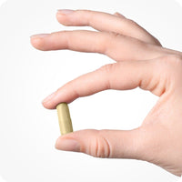 Conceive Plus Morning Sickness Relief single vegan capsule held between two fingers on a white background.