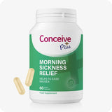 Conceive Plus Morning Sickness Relief supplement bottle with 60 vegan capsules to ease nausea during pregnancy. Green and white label features calming graphics and highlights ginger root as a key ingredient. Two soft yellow capsules are shown beside the bottle.