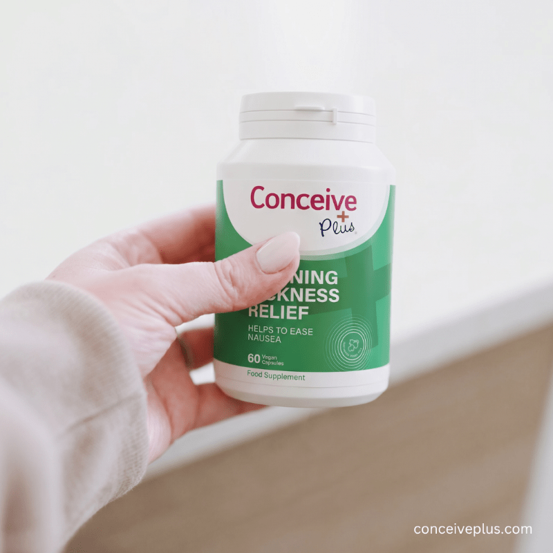 Hand holding a bottle of Conceive Plus morning sickness relief supplement against a light background