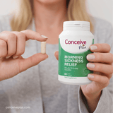 Person holding a bottle of Conceive Plus morning sickness relief supplement and a pill.