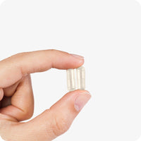 Close-up of hand holding two Conceive Plus Motility Support capsules for men, shown against a white background. Capsules are light yellow and support sperm motility and male fertility.