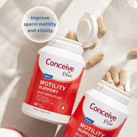 Two bottles of Conceive Plus Men's Motility Support dietary supplement capsules arranged on a light beige surface with scattered capsules and a glass in the background. A white circular badge reads 'Improve sperm motility and vitality.